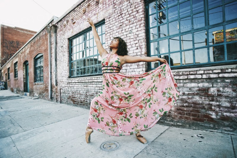 Mixed race ballet dancer wearing dress on sidewalk