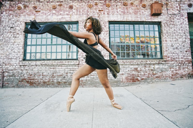 Mixed race woman dancing ballet on sidewalk