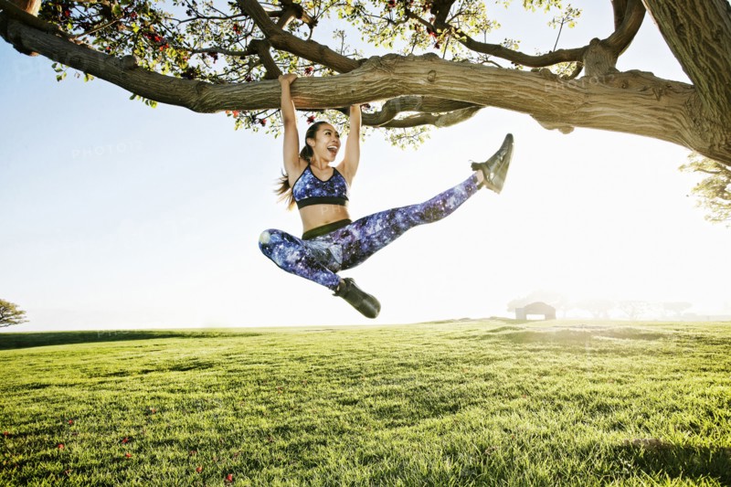 Happy mixed race woman hanging on tree branch