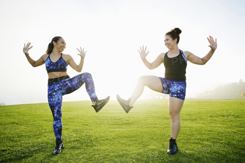 Mixed race women standing on one leg in field