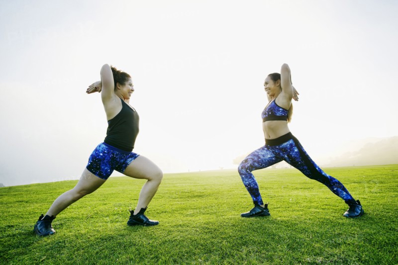 Mixed race women stretching arms in field