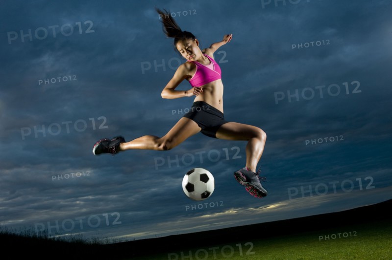 Japanese woman playing soccer at night