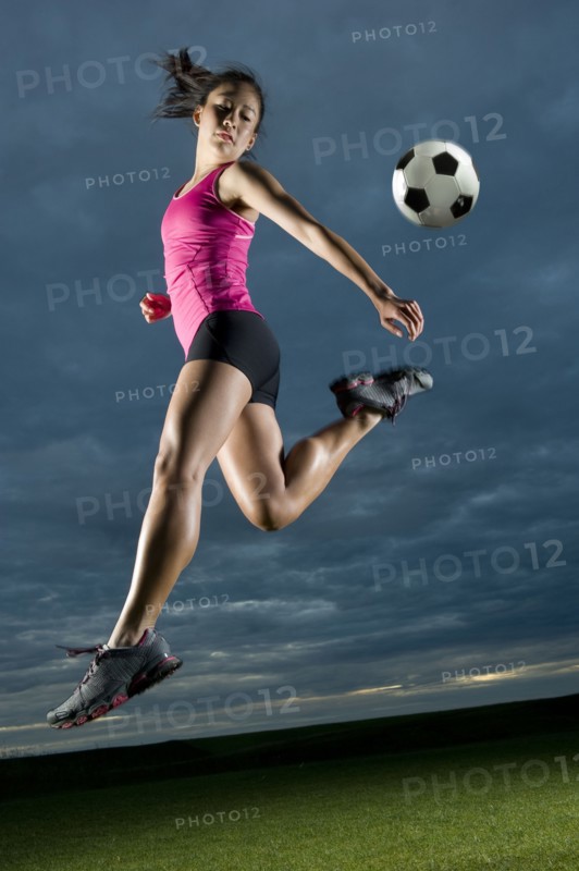 Japanese woman playing soccer at night