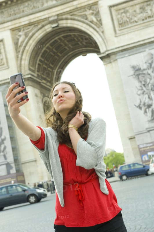 Caucasian woman taking self-portrait near Arc de Triomphe