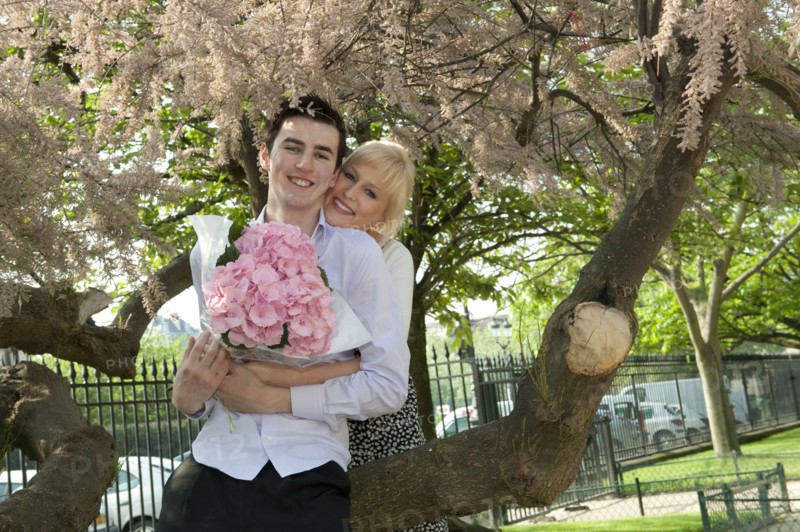 Caucasian couple with flowers kissing in park