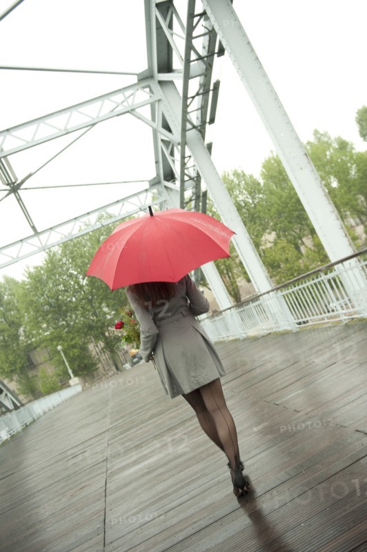 Caucasian woman walking in rain with red umbrella