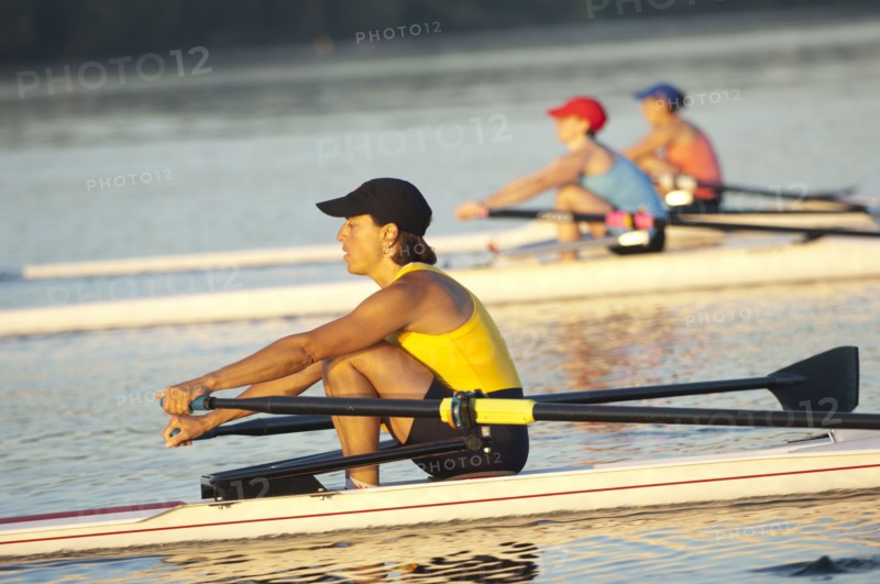 People rowing sculling boats on river