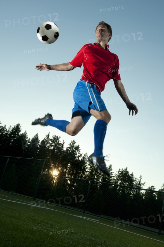 Soccer player jumping in mid-air kicking ball