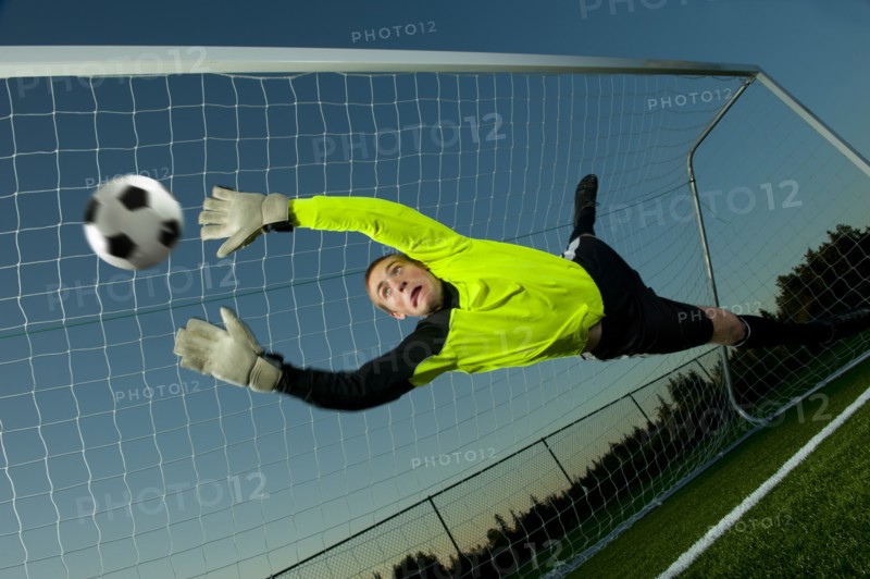 Caucasian soccer goalie jumping in mid-air catching ball