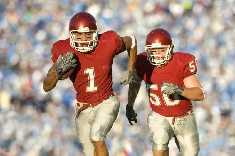 Football players running on field in game