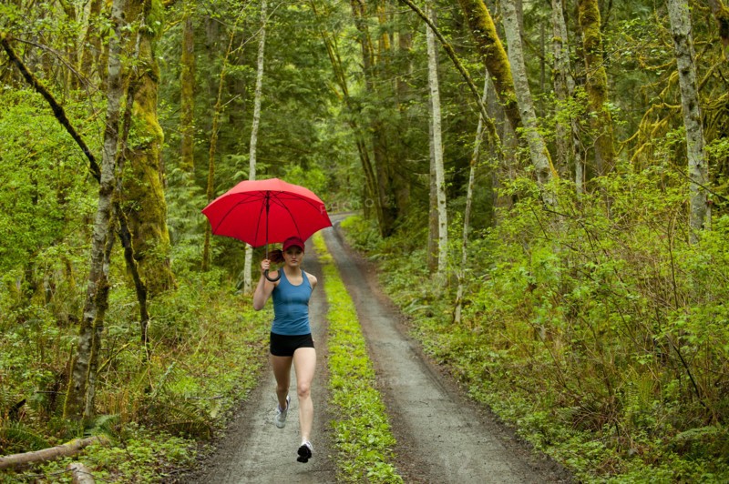 Mixed race runner training on remote road with umbrella