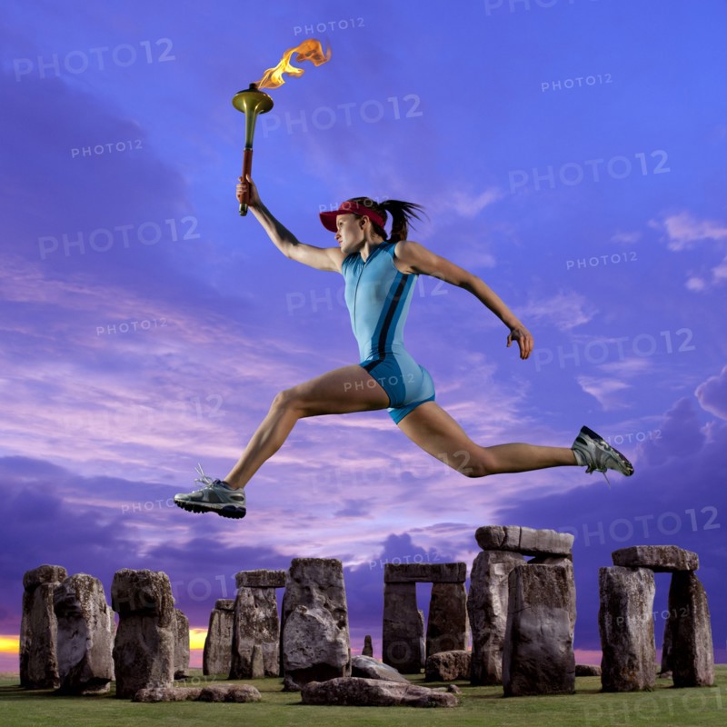 Athlete running with Olympic torch near Stonehenge