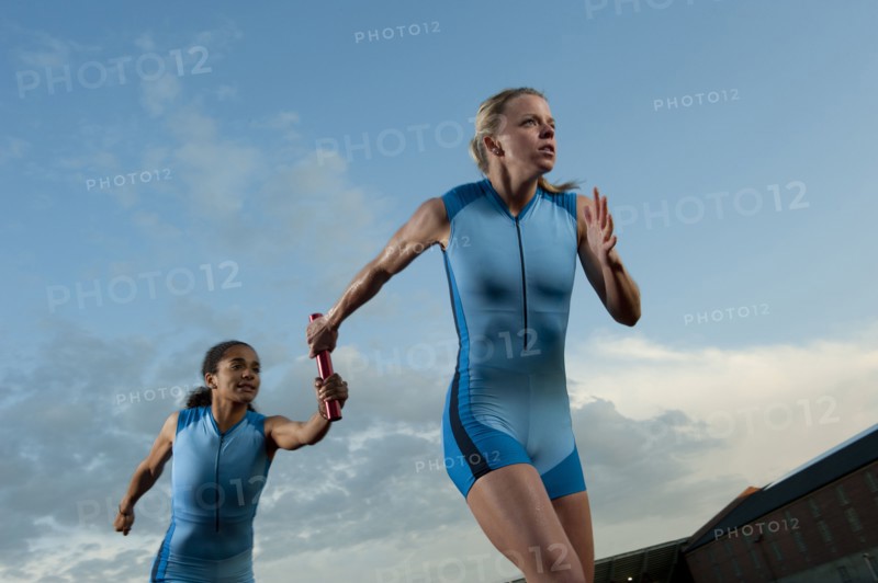 Runners passing baton in relay race