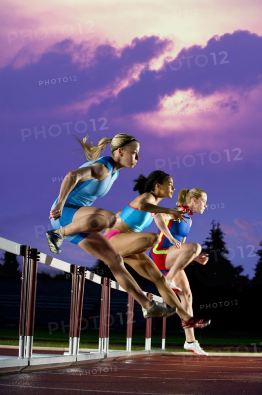 Runners jumping hurdles in race