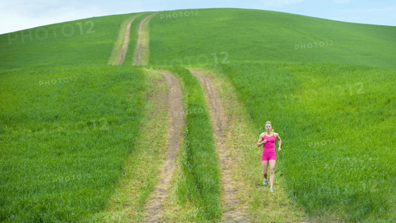 Caucasian woman running on path through field