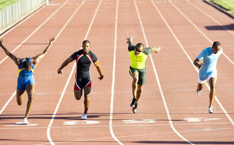Runners running across finish line on track in race