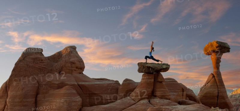 Caucasian woman practicing yoga on top of rock formation