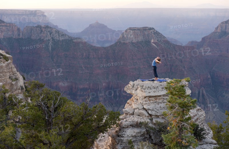 Caucasian woman practicing yoga on top of rock formation