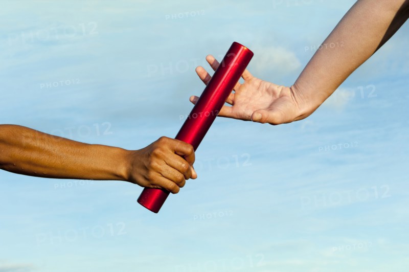 Runner passing baton to teammate