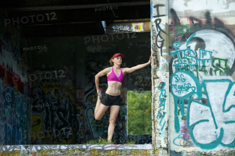 Caucasian woman stretching in abandoned loading dock