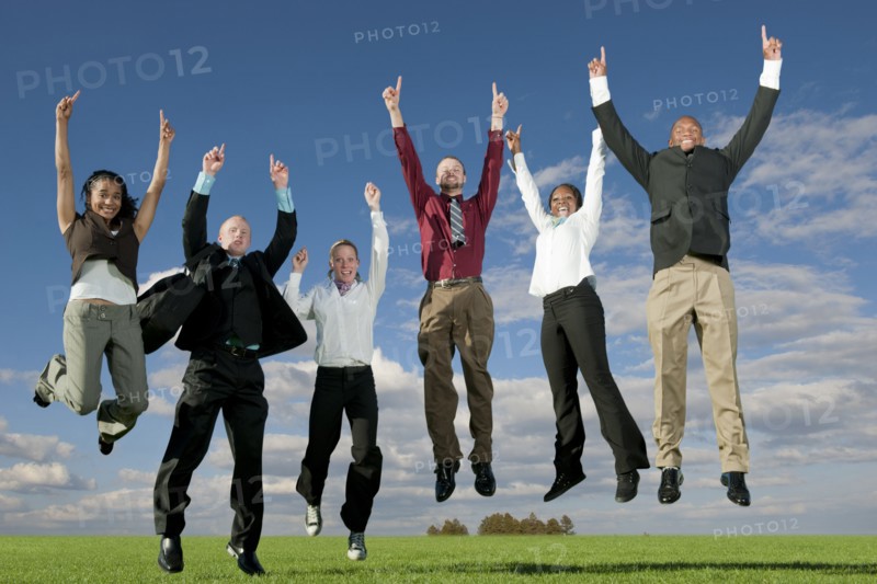 Business people jumping and cheering in field
