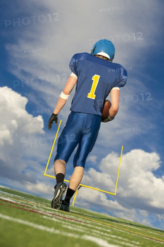 Caucasian football player carrying football