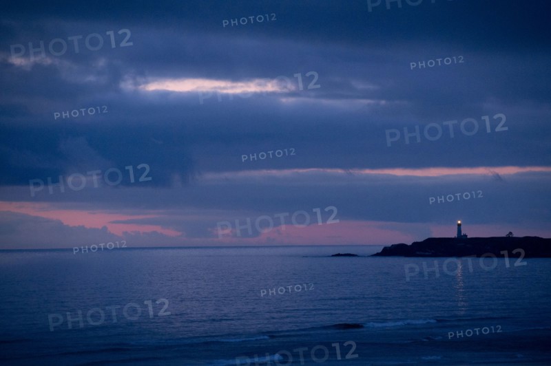 Lighthouse beaming from coastline at night