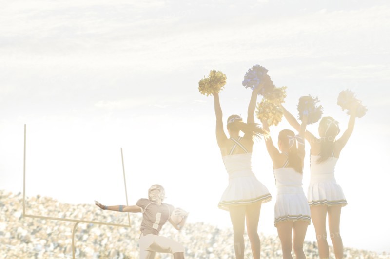 Caucasian cheerleaders on sidelines at football game