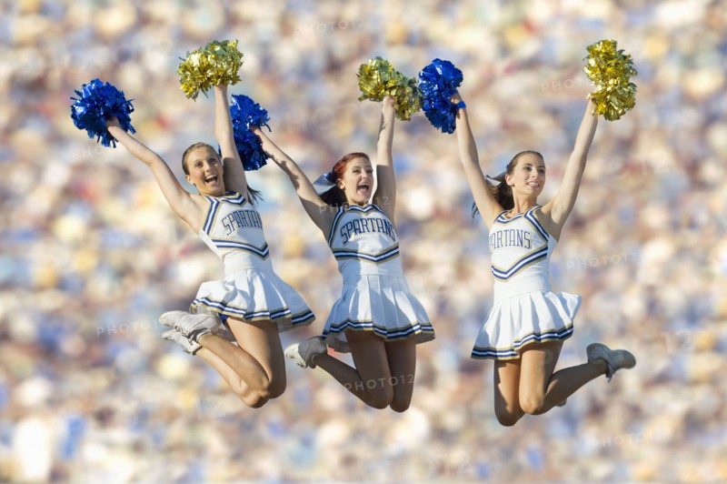 Caucasian cheerleaders jumping in mid-air