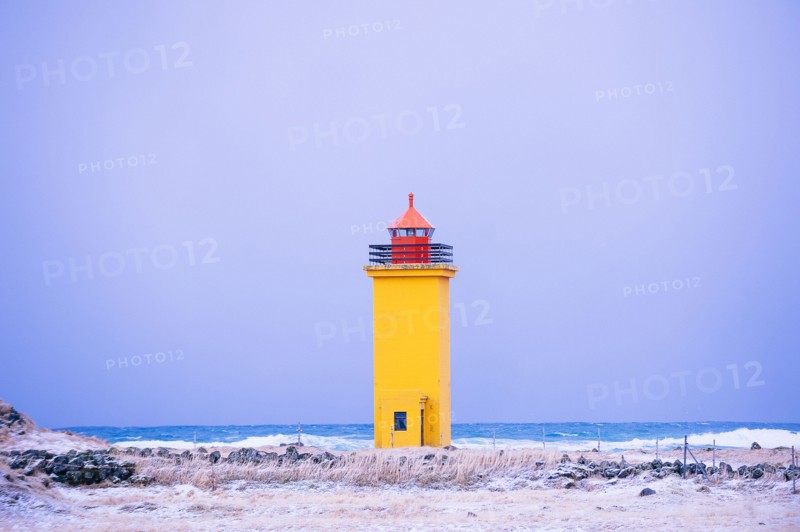 Yellow lighthouse on snowy coastline