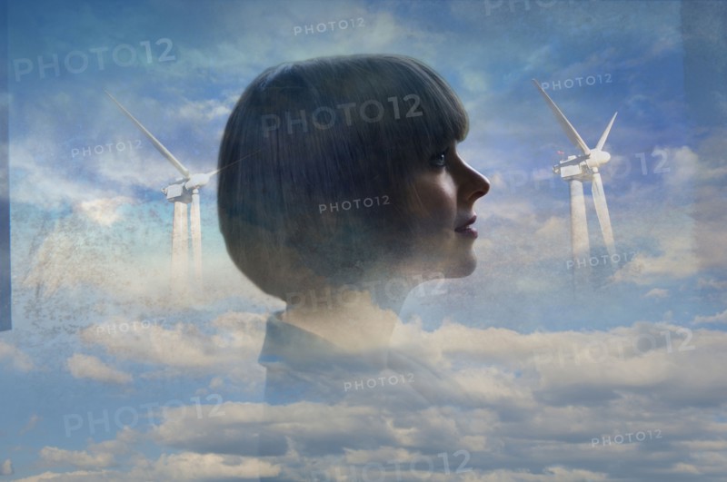 Double exposure of businesswoman and wind turbines in clouds