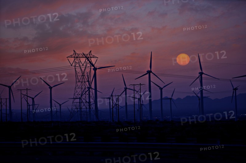 Silhouette of wind turbines and power lines at sunset