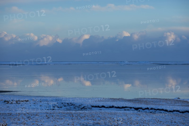 Clouds reflected in still ocean in arctic landscape