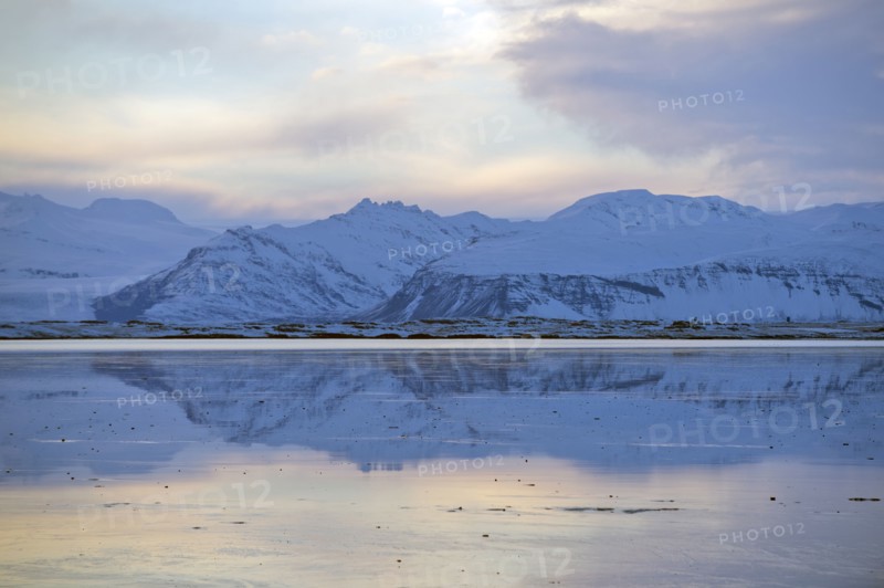Mountains reflected in still ocean in arctic landscape