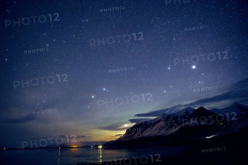 Starry sky over still ocean in arctic landscape