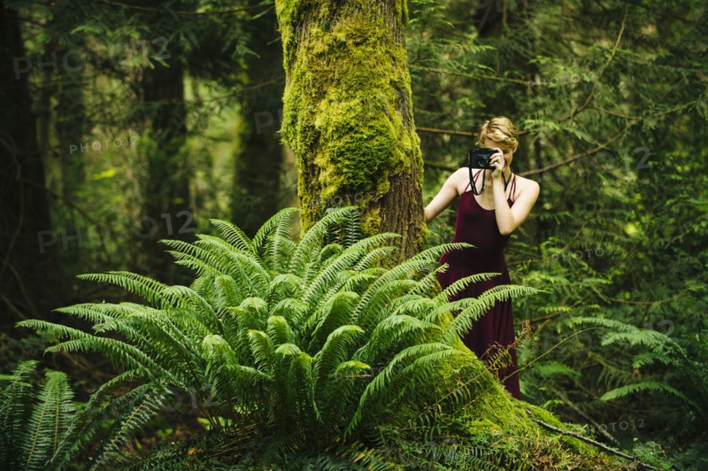 Caucasian woman taking photograph in forest