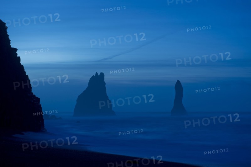 Rock formations in ocean at misty beach