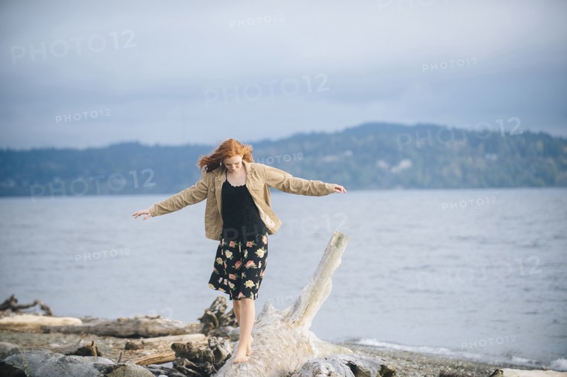 Girl balancing on driftwood on beach