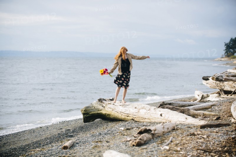 Girl balancing on driftwood on beach