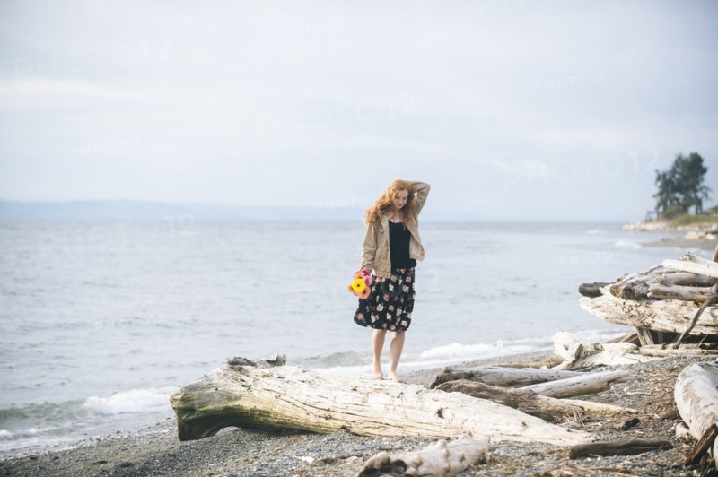Girl standing on driftwood on beach