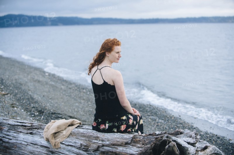 Girl sitting on driftwood on beach