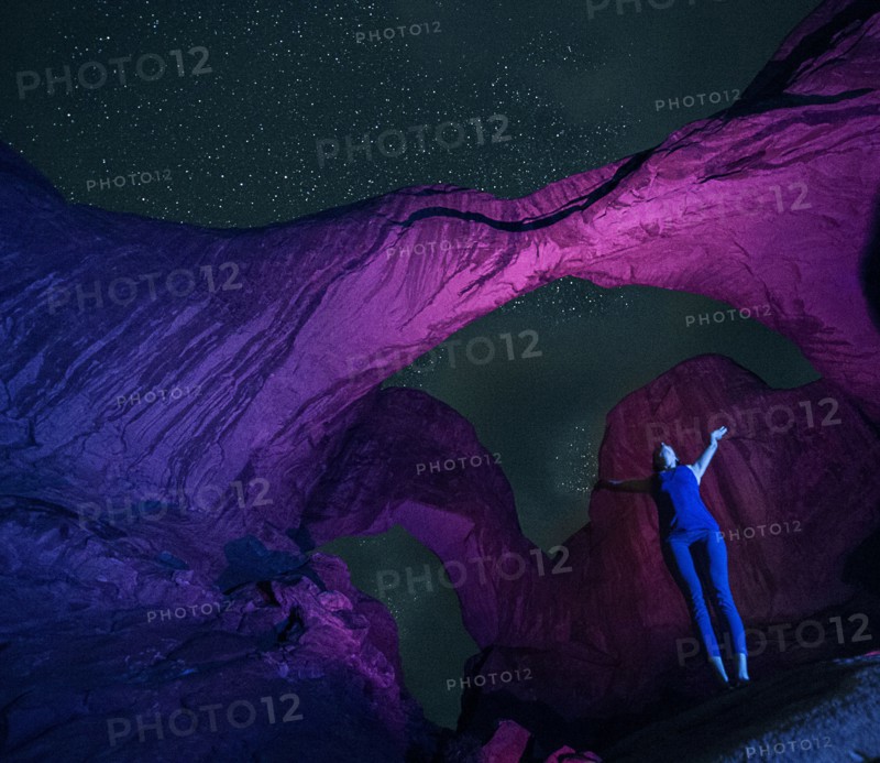 Woman standing in illuminated rocks at night in Arches National Park