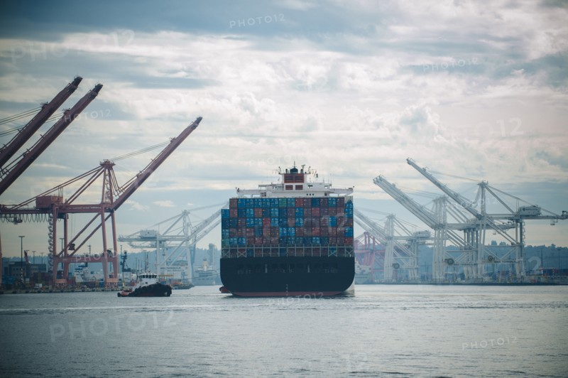 Tugboat and container ship in industrial harbor