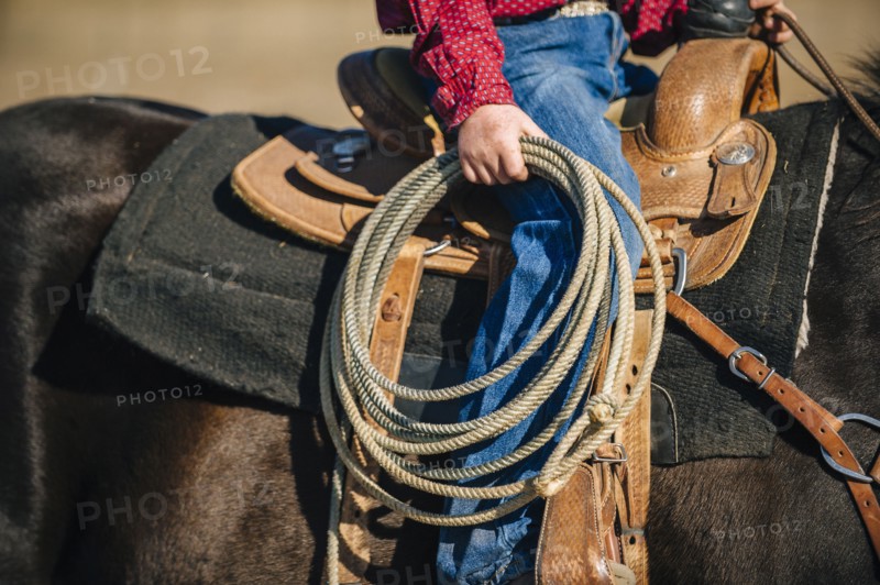 Caucasian boy carrying lasso and riding horse