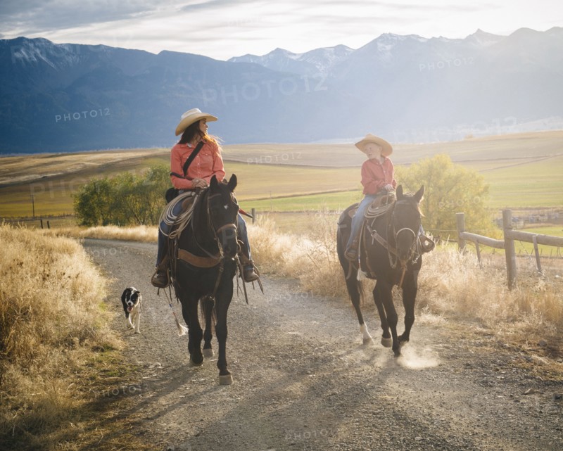 Caucasian mother and son riding horses on ranch