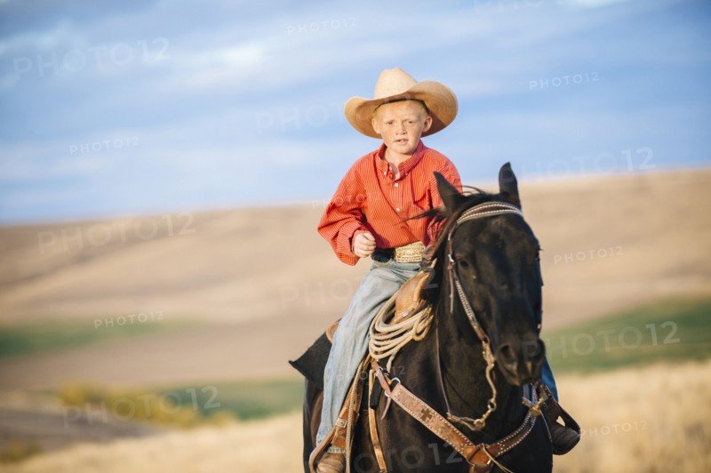 Caucasian boy riding horse in grassy field