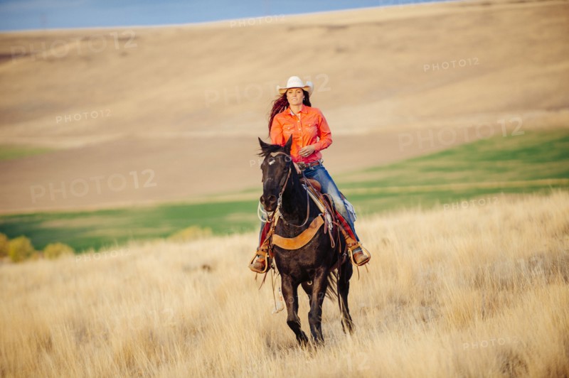 Caucasian woman riding horse in grassy field
