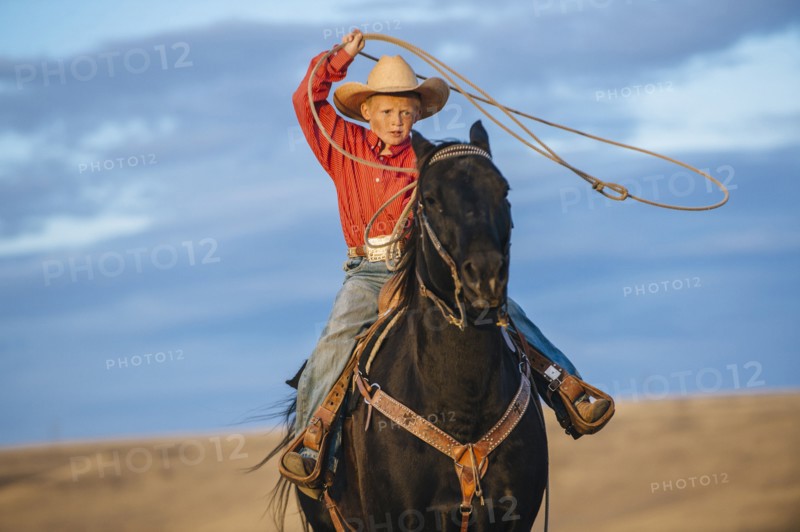 Caucasian boy on horse throwing lasso