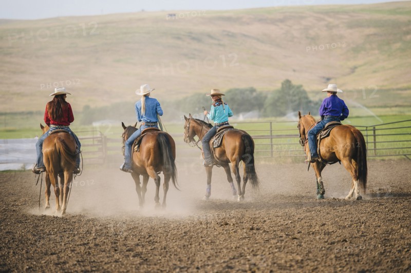 Cowgirls and cowboy riding horses on ranch