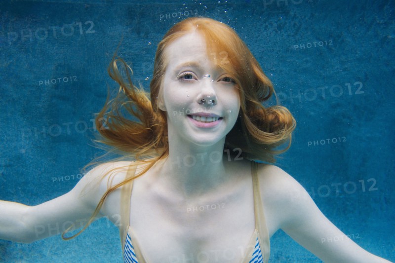 Caucasian woman smiling underwater in swimming pool